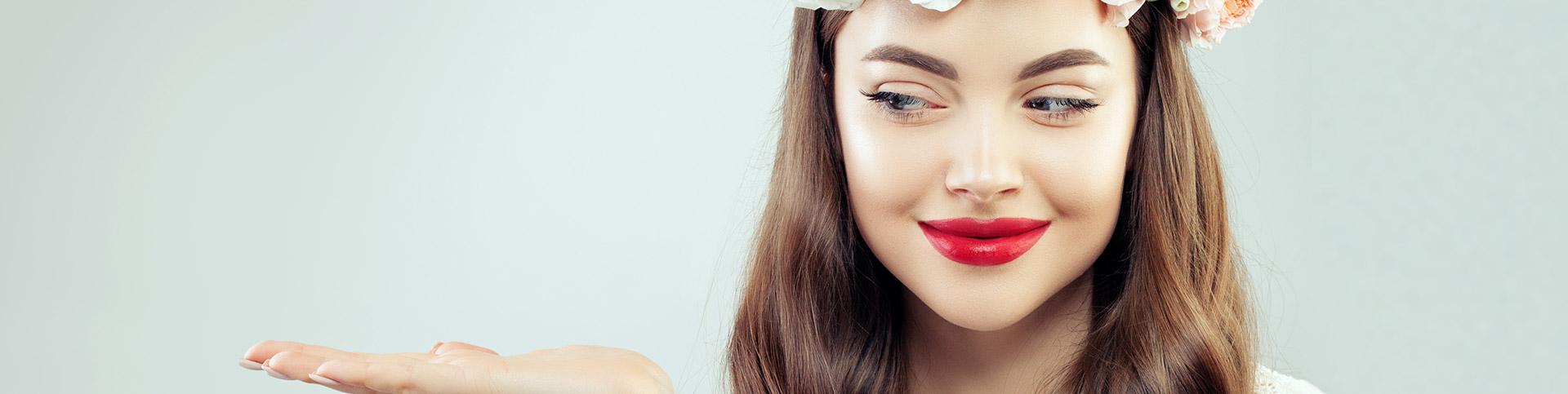 A woman with red lipstick holding out her hand and looking to the left with her eyes