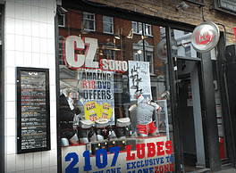 A discreet store front with a sign, offering a variety of adult novelty items inside.