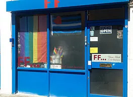 Blue storefront with rainbow flag on door, LGBTQ+ friendly shop.