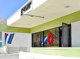 A green and white building with a sign that says gear, located in a bustling city street.